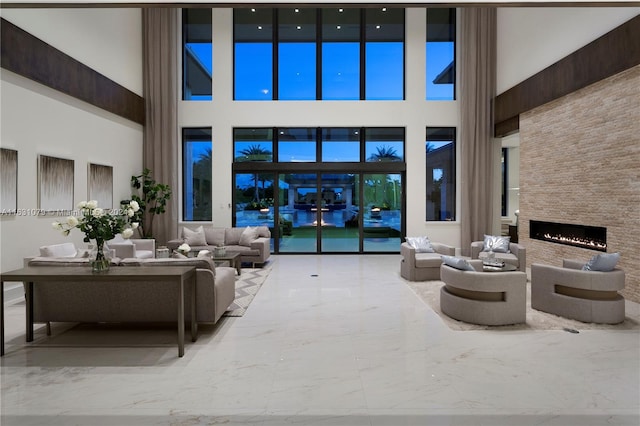 tiled living room with a stone fireplace and a high ceiling