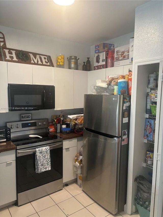 kitchen with appliances with stainless steel finishes, white cabinetry, and light tile patterned floors