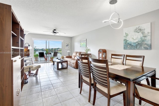 tiled dining space with a textured ceiling and ceiling fan