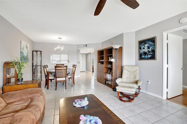 tiled living room with ceiling fan and a textured ceiling