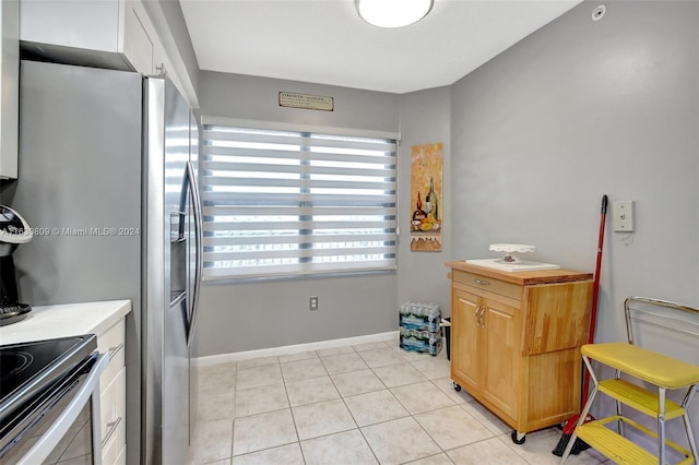 kitchen with light tile patterned floors and stainless steel fridge