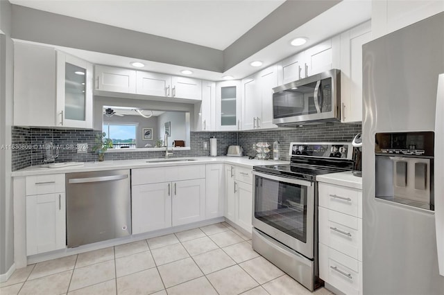 kitchen with appliances with stainless steel finishes, white cabinets, sink, and ceiling fan