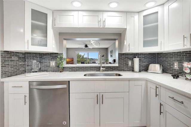 kitchen with stainless steel dishwasher, sink, white cabinets, and backsplash