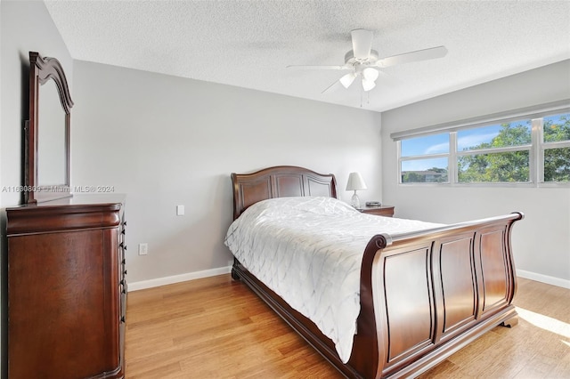 bedroom featuring light hardwood / wood-style floors, a textured ceiling, and ceiling fan