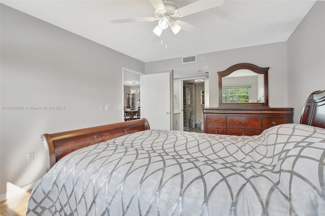 bedroom with a textured ceiling, hardwood / wood-style flooring, and ceiling fan