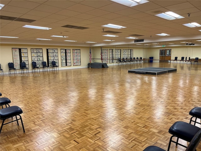 gym featuring a paneled ceiling and light parquet floors