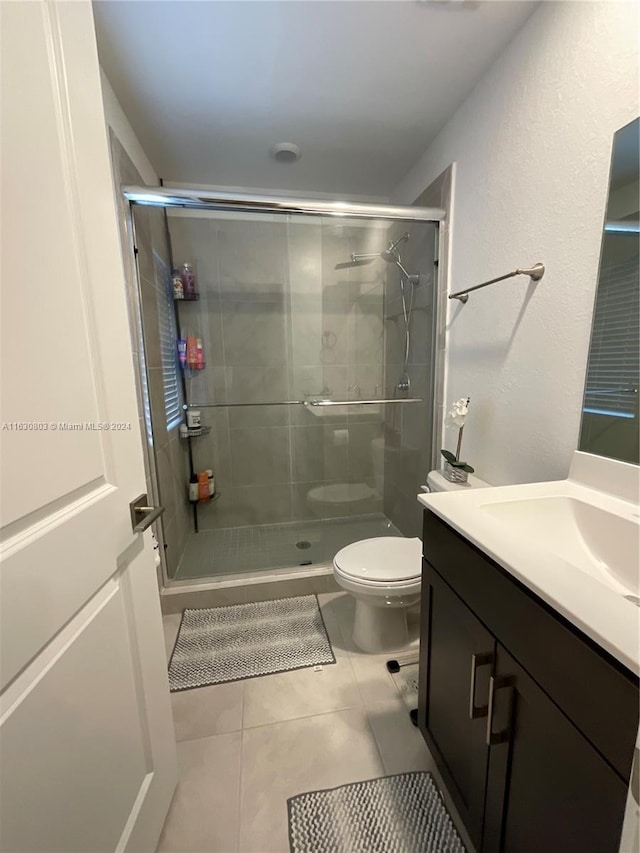 bathroom featuring vanity, walk in shower, tile patterned flooring, and toilet