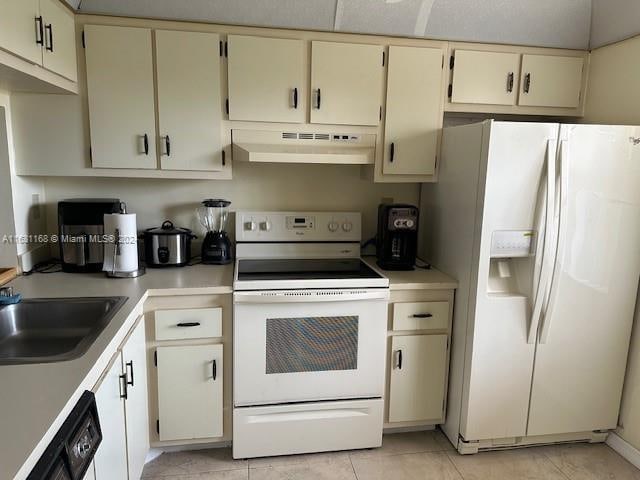 kitchen featuring light tile patterned floors, sink, cream cabinets, and white appliances