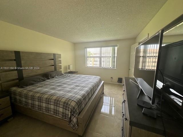 bedroom with a textured ceiling and tile patterned floors