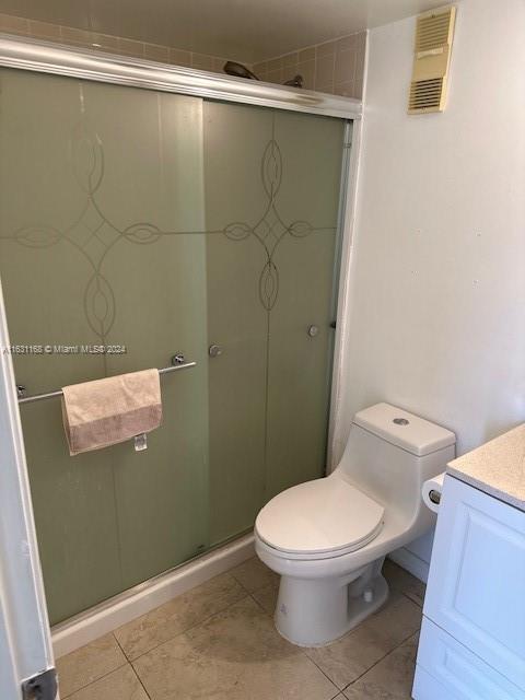 bathroom with toilet, an enclosed shower, tile patterned flooring, and vanity