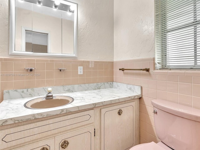 bathroom featuring vanity, toilet, and tile walls