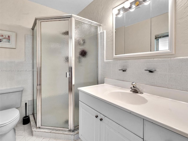 bathroom featuring vanity, toilet, a shower with door, and tile walls