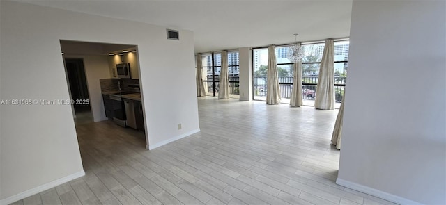 unfurnished room with floor to ceiling windows and light hardwood / wood-style floors