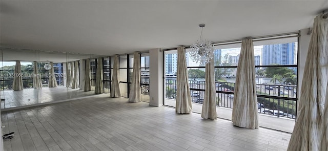 unfurnished dining area with an inviting chandelier, light hardwood / wood-style flooring, and floor to ceiling windows