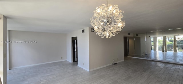 unfurnished room featuring an inviting chandelier and wood-type flooring