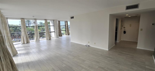 unfurnished room featuring floor to ceiling windows and light hardwood / wood-style floors