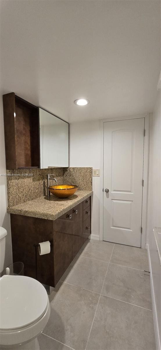 bathroom with tasteful backsplash, vanity, toilet, and tile patterned flooring