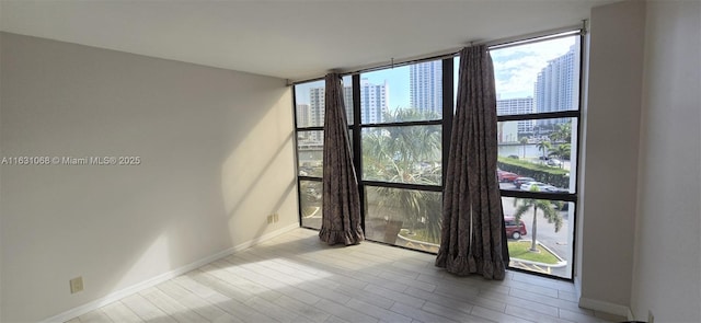 unfurnished room featuring a wall of windows and light wood-type flooring