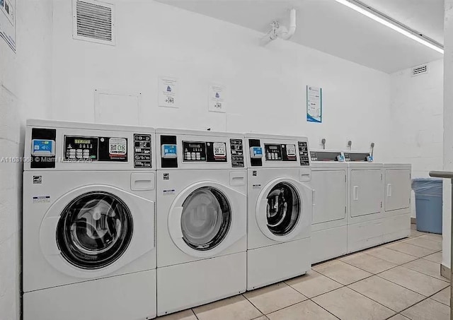 clothes washing area with light tile patterned floors and independent washer and dryer