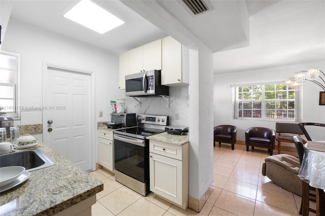 kitchen with light tile patterned floors, stainless steel appliances, decorative backsplash, white cabinets, and sink