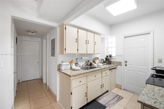 kitchen featuring light tile patterned floors, backsplash, electric panel, light stone counters, and sink