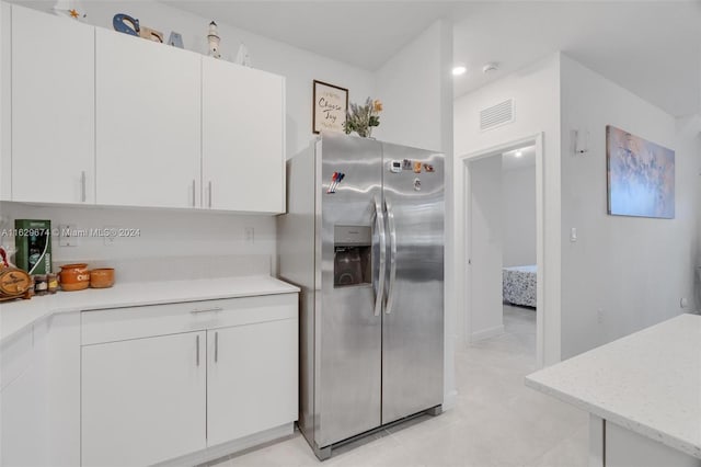 kitchen featuring white cabinets, stainless steel fridge, and light tile patterned floors