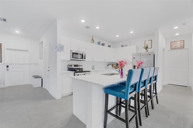 kitchen featuring white cabinetry, a kitchen island with sink, stainless steel appliances, a kitchen breakfast bar, and sink