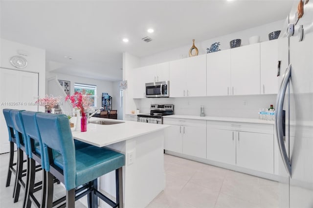 kitchen featuring a center island with sink, appliances with stainless steel finishes, sink, and white cabinets