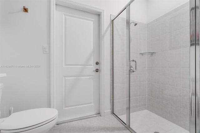 bathroom with an enclosed shower, tile patterned flooring, and toilet