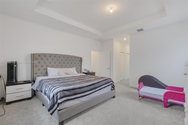 bedroom featuring a closet, a tray ceiling, and light colored carpet