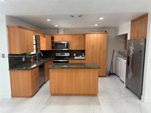 kitchen with decorative backsplash, a kitchen island, washer and dryer, and stainless steel appliances