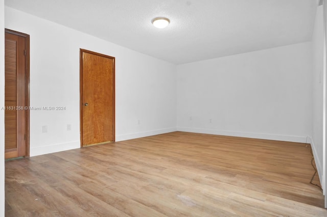 unfurnished room with a textured ceiling and light hardwood / wood-style floors