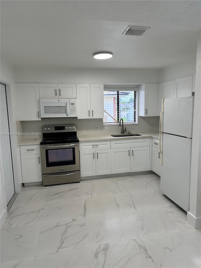 324 E 34th St, Hialeah, FL 33013 - kitchen featuring white appliances, light marble finish flooring, white cabinets, light countertops, and a textured ceiling