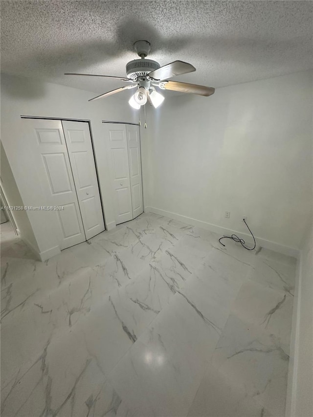 324 E 34th St, Hialeah, FL 33013 - unfurnished bedroom with multiple closets, light marble finish floors, a ceiling fan, and a textured ceiling