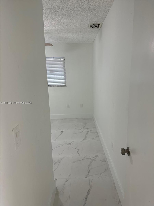 empty room with ceiling fan and a textured ceiling