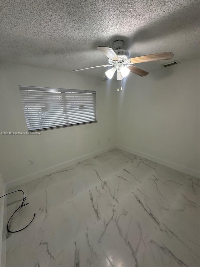 empty room with ceiling fan and a textured ceiling