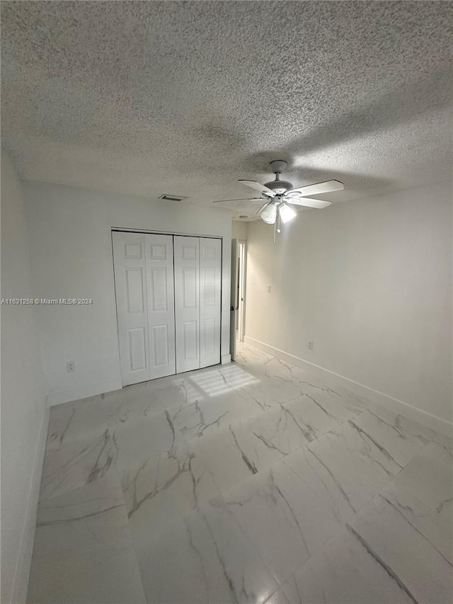 unfurnished bedroom with a textured ceiling, ceiling fan, and a closet