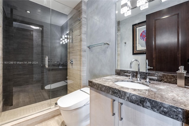 bathroom featuring toilet, vanity, and a shower with shower door