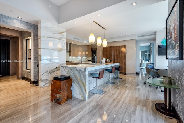 17749 Collins Ave Unit 1802, Sunny Isles Beach, FL 33160 - kitchen featuring modern cabinets, light wood-style floors, a kitchen breakfast bar, pendant lighting, and a large island