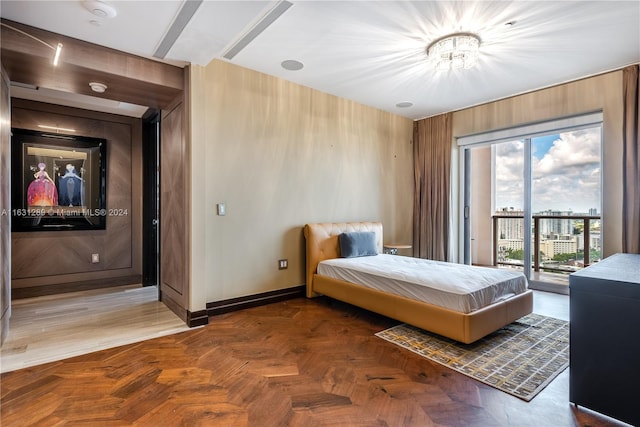 bedroom with multiple windows, parquet floors, access to outside, and wood walls