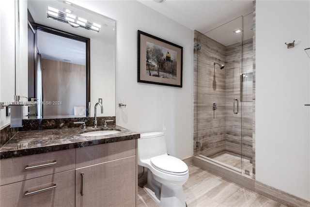 bathroom featuring a shower with door, toilet, and vanity