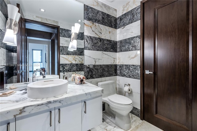 bathroom featuring tile patterned flooring, tile walls, toilet, and vanity