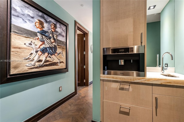 kitchen featuring sink, light brown cabinets, dark parquet flooring, and stainless steel oven