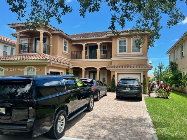 mediterranean / spanish home featuring a balcony, a garage, and a front yard