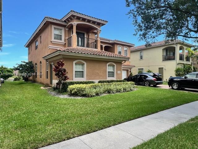 view of front of house with a front lawn and a balcony