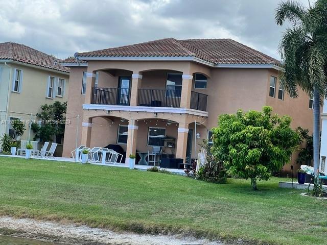 back of house featuring a balcony and a yard