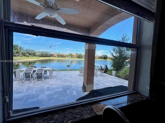 doorway to outside with a water view and ceiling fan