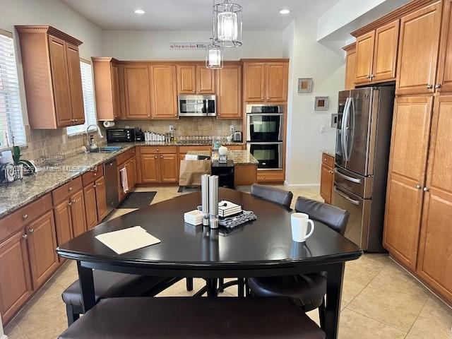 kitchen with pendant lighting, sink, stainless steel appliances, a kitchen island, and decorative backsplash