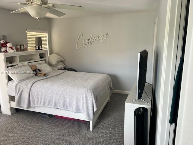 bedroom featuring ceiling fan and dark carpet