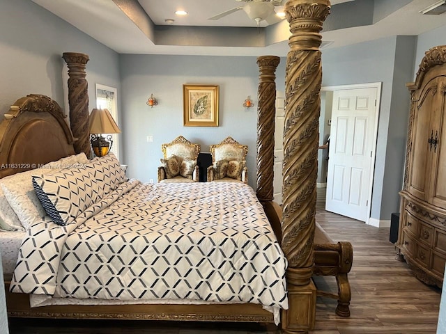 bedroom featuring a raised ceiling, dark hardwood / wood-style floors, and ceiling fan